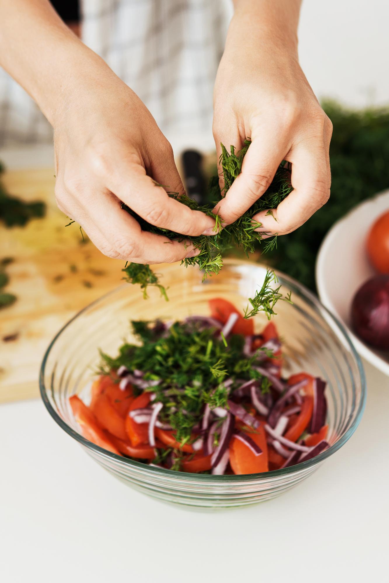 Hands arranging herbs on dish